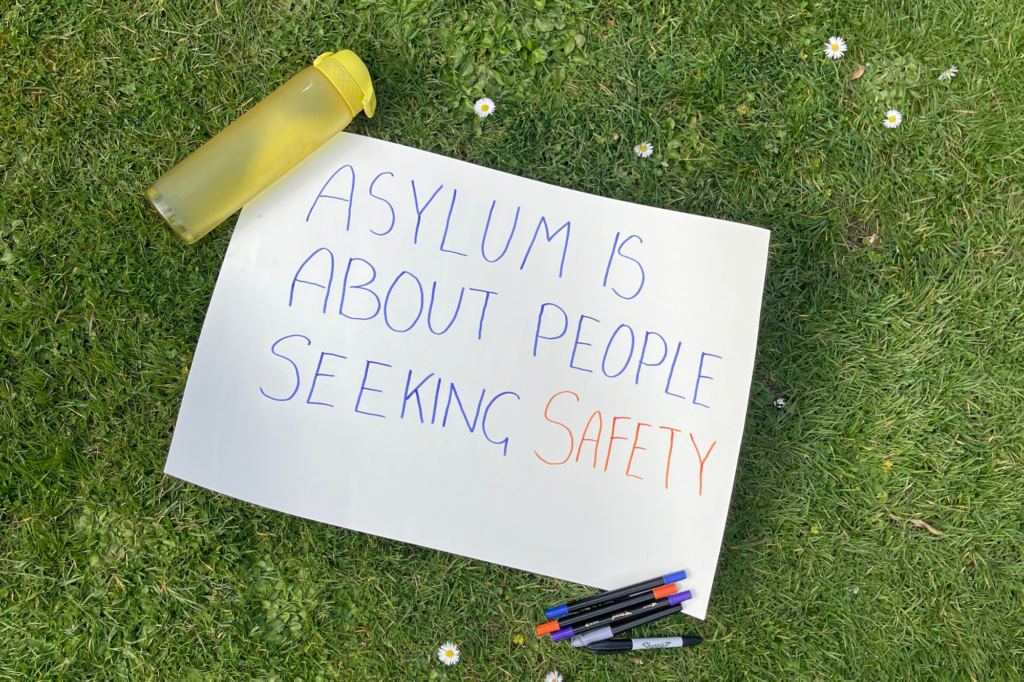 A poster reading "Asylum is about seeking safety"